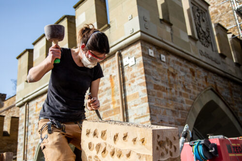 Vor historischer Kulisse arbeitet Steinmetzin Marie-Elaine Boos nach traditioneller Handwerkskunst.